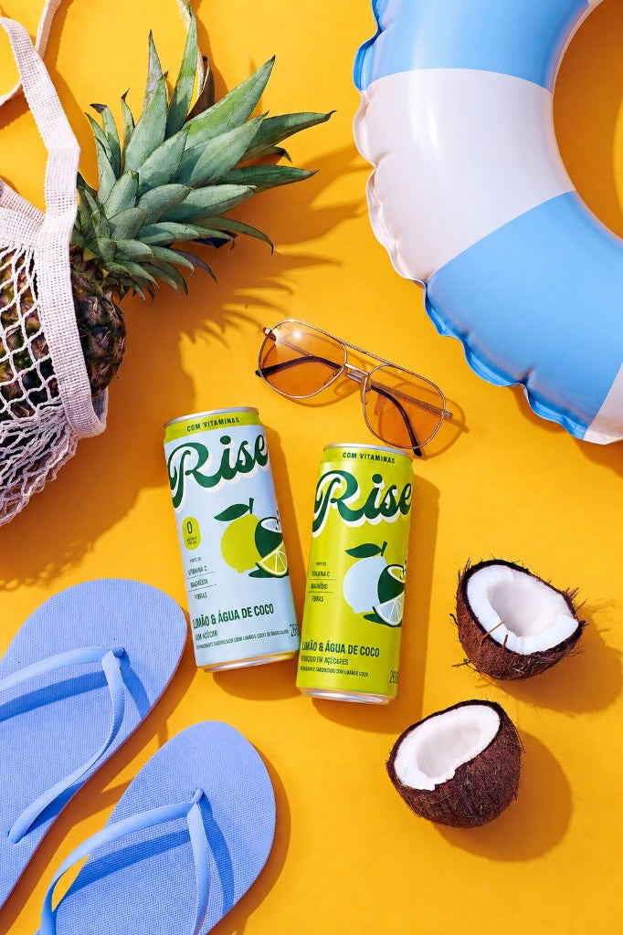 Latas Rise em uma composição de verão com frutas e acessórios